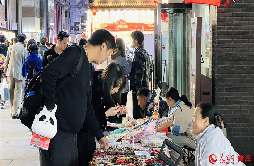 夜晚集市上擺攤的攤主和挑選商品的顧客。人民網(wǎng) 顧斐菲攝